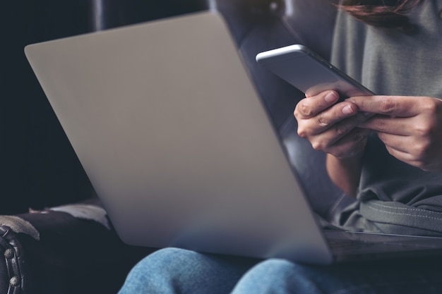 A woman using mobile phone while working on laptop