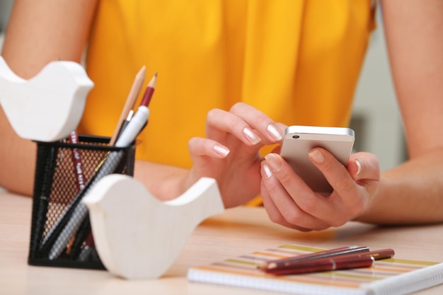 Woman using mobile phone on workplace close up