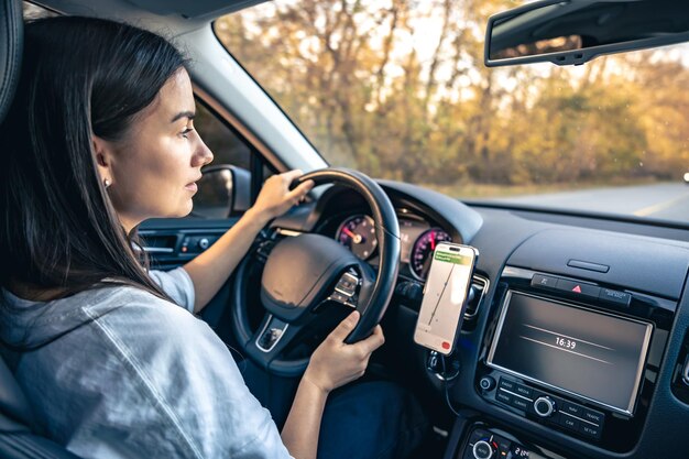 Foto donna che usa l'app di navigazione sullo smartphone mentre guida un'auto