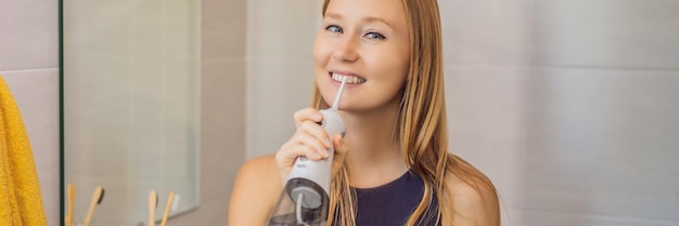 Woman using an oral irrigator in bathroom banner long format