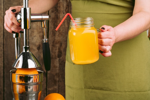 Donna che per mezzo dell'apparato degli spremiagrumi arancio a casa