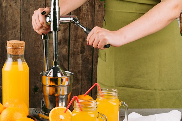 Woman using orange juicer apparatus at home