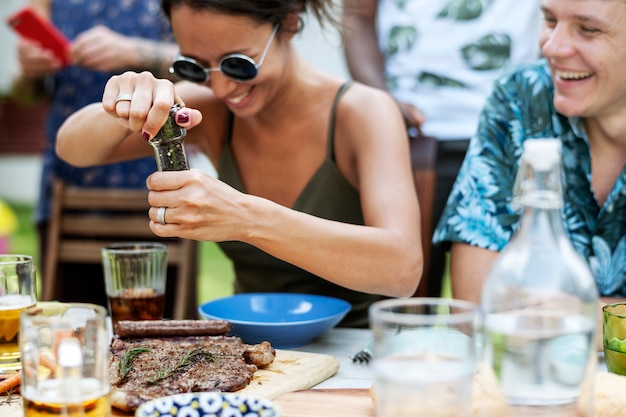 A woman using a pepper grinder at a meal