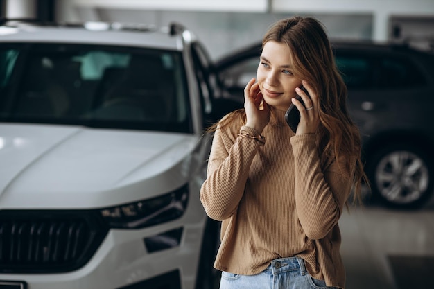 Woman using phone by her new car