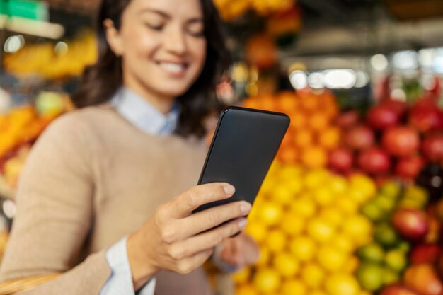 Foto una donna che usa un telefono al mercato degli agricoltori si concentra selettivamente sulla mano