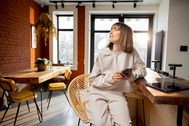 Woman using phone while sitting in modern studio apartment