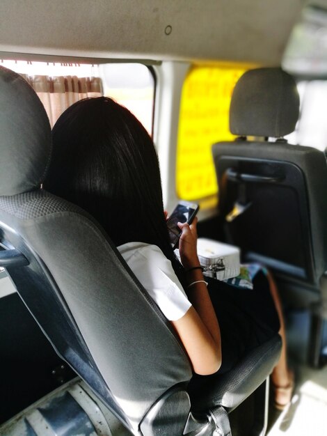 バスで旅している間女性が電話を使っています