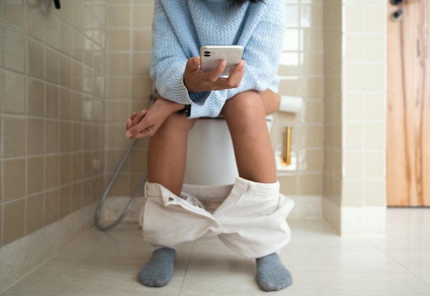 写真 トイレを使いながら電話を使う女性