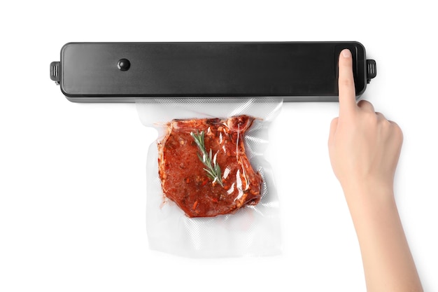 Woman using sealer for vacuum packing and plastic bag with meat steak rosemary on white background