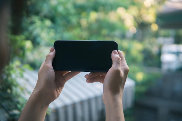 スマートフォンの画面に触れる屋外でスマートフォンを使用してメッセージを送信する女性