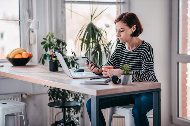 Woman using smart phone and drinking coffee