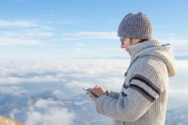 Woman using smart phone on the mountains. 