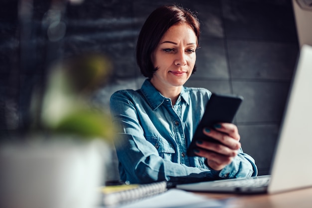 オフィスでスマートフォンを使用して女性