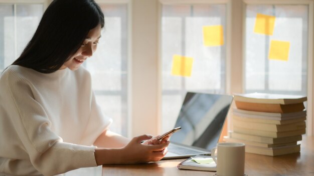 カフェのテーブルでスマートフォンを使っている女性