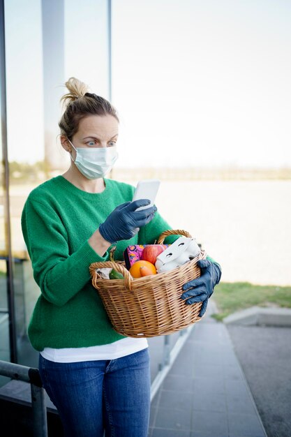 Foto donna che usa lo smartphone mentre tiene il cesto all'aperto