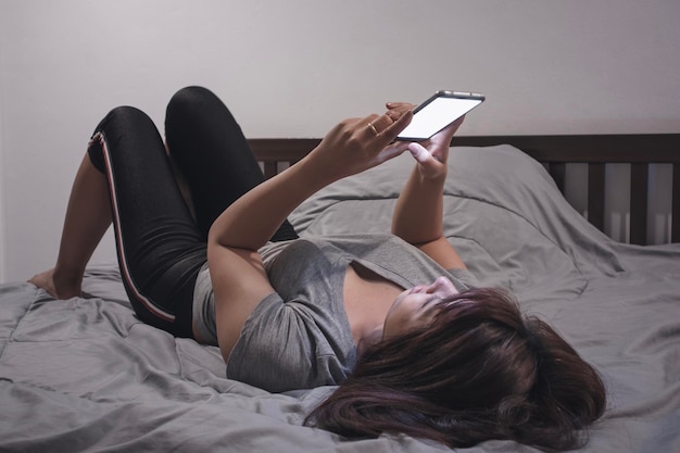 Photo woman using smart phone while lying on bed at home