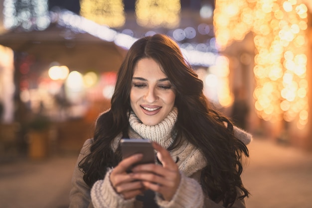 Woman using smart phone while standing on the street.