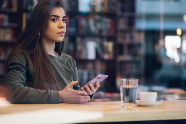 写真 カフェでスマホを操作しながらコーヒーを飲む女性