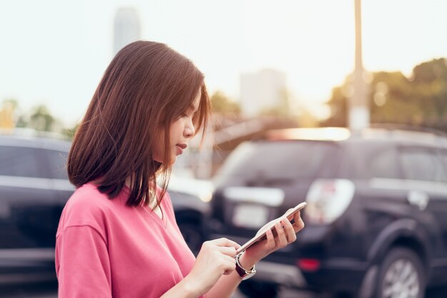 Woman using smartphone for the application on car blur background.