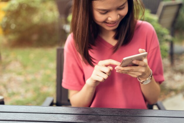 Donna che utilizza smartphone per l'applicazione sul tavolo in park cafe. concetti per la tecnologia digitale