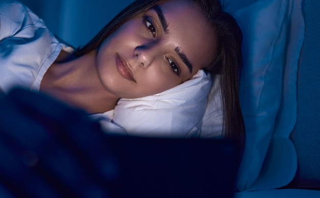 Foto donna che utilizza lo smartphone a letto con prima di dormire