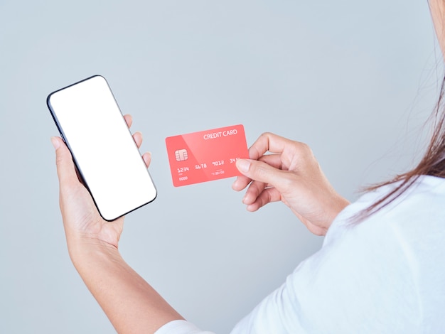 Woman using smartphone and credit card for online shopping, payments or checks bank account.