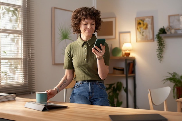 Woman using smartphone and drinking coffee