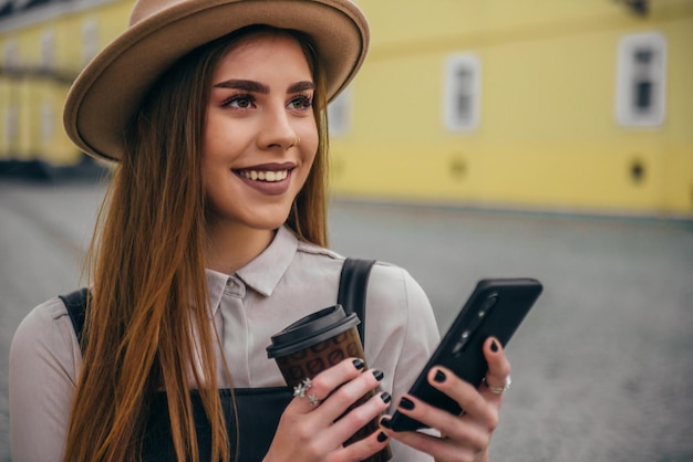 Woman using smartphone and drinking coffee