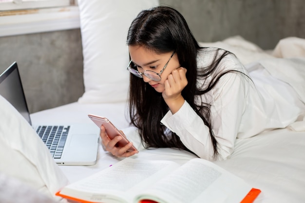 Woman using smartphone on her bed