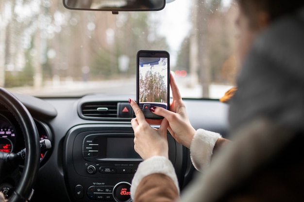 写真 冬の遠征中に車の中でスマートフォンを使用している女性