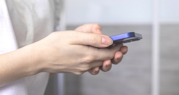 Woman using a smartphone indoors at home, woman holding mobile phone in hand, leisure time concept photo