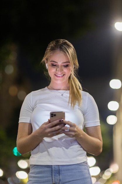 Donna che usa uno smartphone di notte per strada tecnologia telefonica mobile urbana