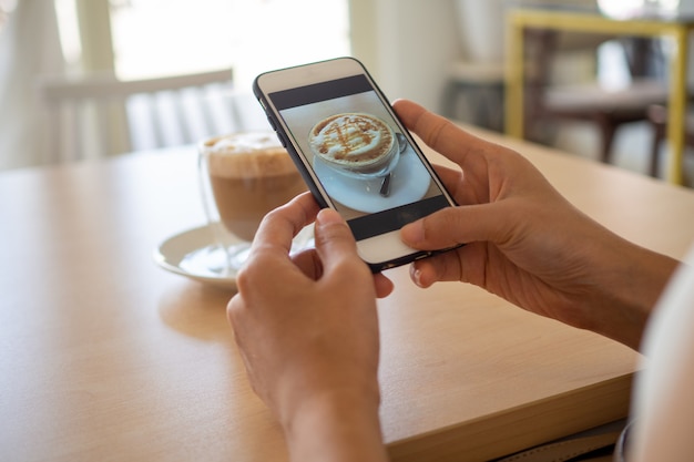 Woman using a smartphone to take photo of a coffee