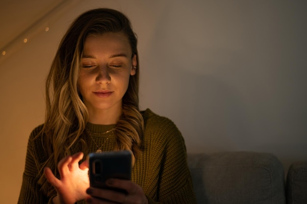 Woman using smartphone while sitting on the sofa at home