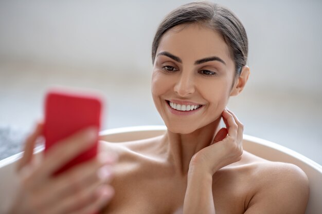 Foto donna che utilizza uno smartphone mentre si fa il bagno