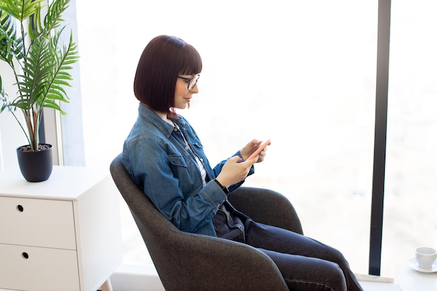 Woman using smartphone while working at modern office