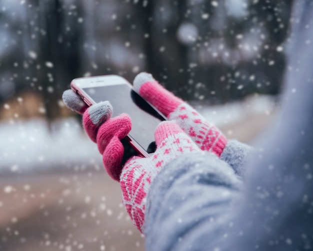 Woman using smartphone in winter with gloves for touch screens