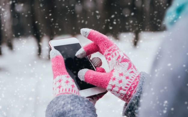 タッチスクリーン用の手袋と冬にスマートフォンを使用している女性