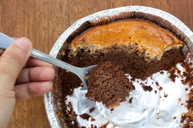 Woman using spoon to cut brownie