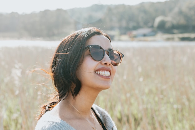 Женщина, использующая солнцезащитные очки улыбается