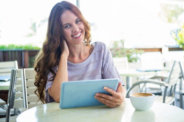 Женщина, используя планшет на террасе кафе