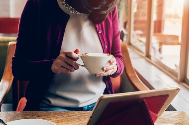 Photo woman using tablet computer in coffee shop with vintage tone.