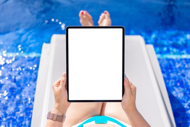 Woman using tablet computer poolside empty vertical screen mockup