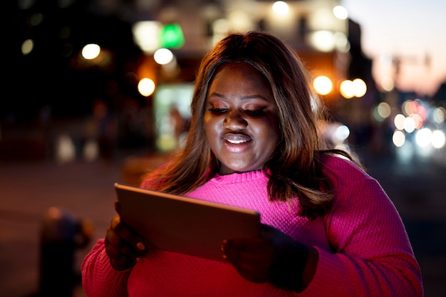 Женщина с помощью планшета ночью в городских огнях
