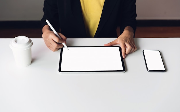 Woman using tablet screen blank and smartphone on the table 