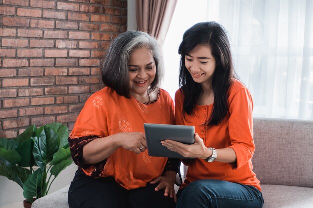 Woman using tablet with her mature mom
