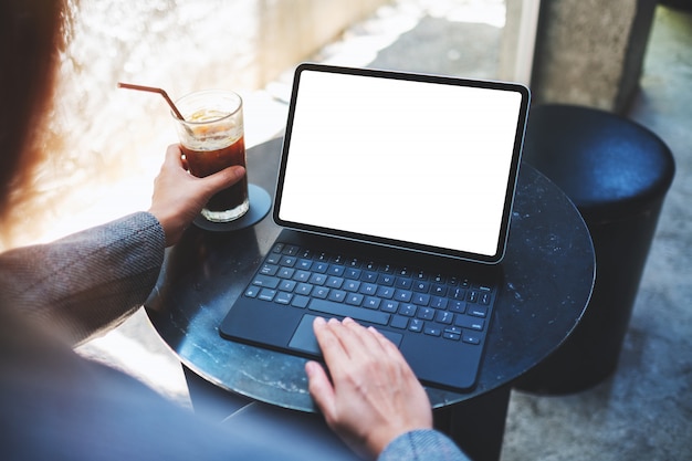  of a woman using and touching on tablet touchpad with blank white desktop screen as a computer pc while drinking coffee