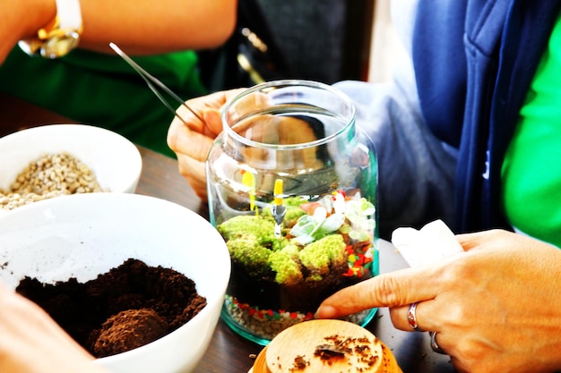 Woman using tweeers making beauty terrarium in clear glass bottle