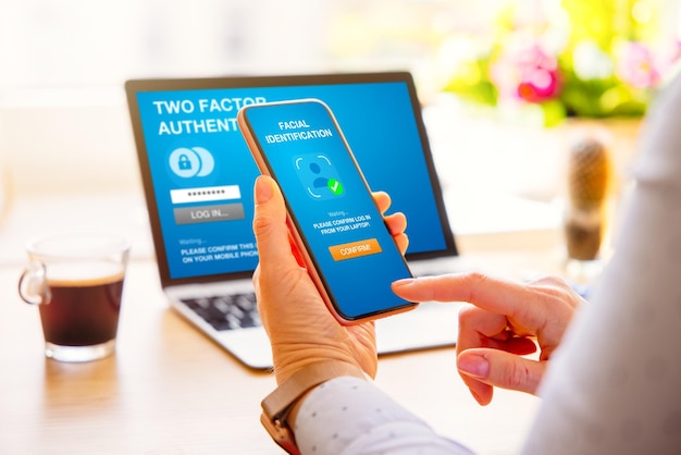 Woman using two factor authentication on laptop computer and mobile phone