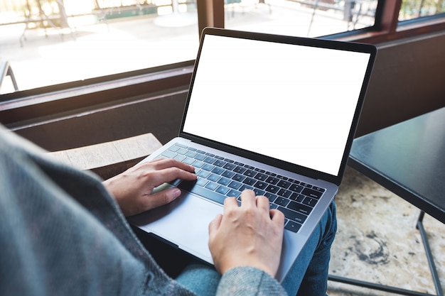 Photo of a woman using and typing on laptop computer keyboard with blank white desktop screen